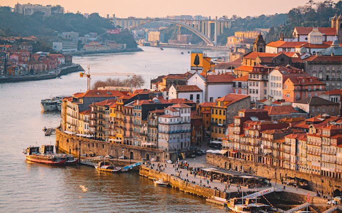 Porto riverside with colorful buildings and boats on the Douro River, viewed from Lisbon day trip.