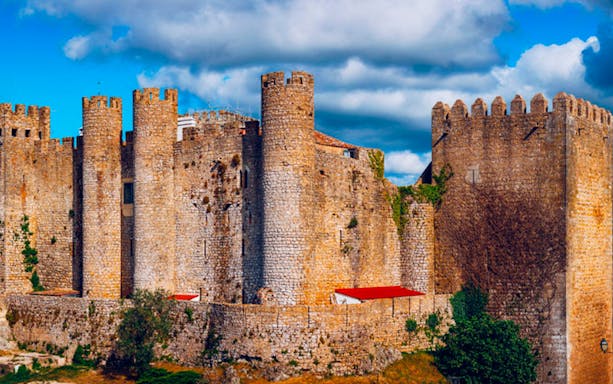Óbidos Castle with stone walls under a blue sky, part of Lisbon day tour to Nazaré and Óbidos.