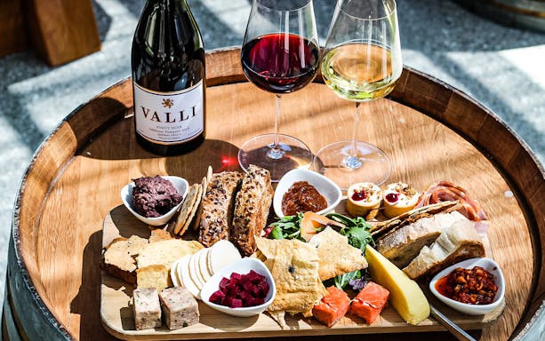 Wine and cheese platter on a wooden barrel during Queenstown guided tour.