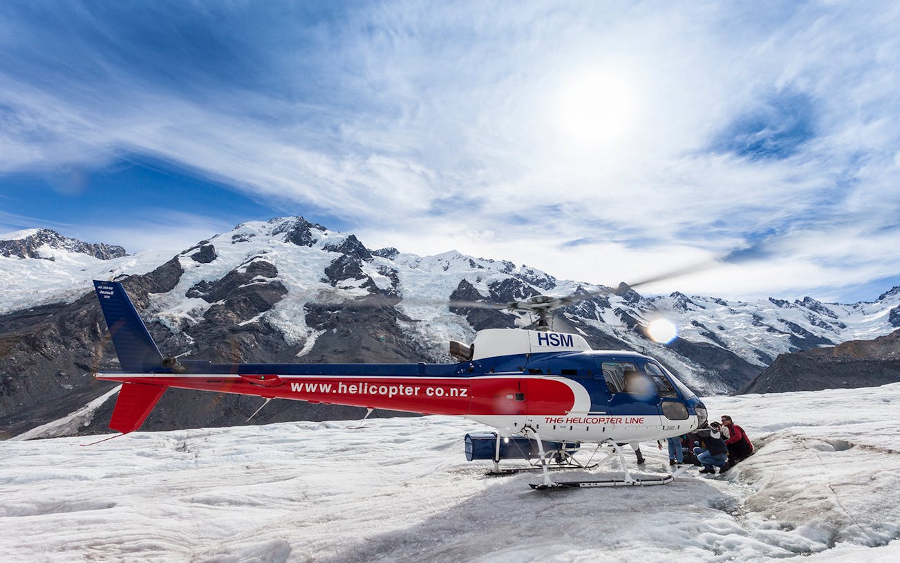 Helicopter on Tasman Glacier with tourists preparing for guided heli-hike tour.