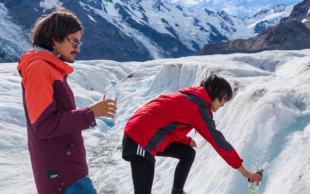 Visitors collecting glacier water during a guided heli-hike on Tasman Glacier, New Zealand.