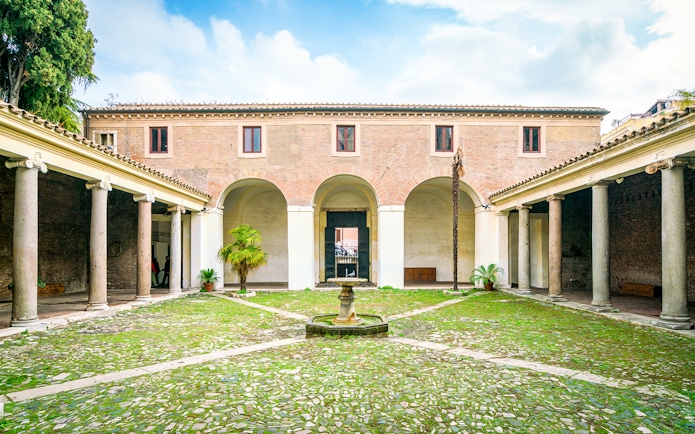Courtyard of Basilica di San Clemente, Rome with columns and central fountain.