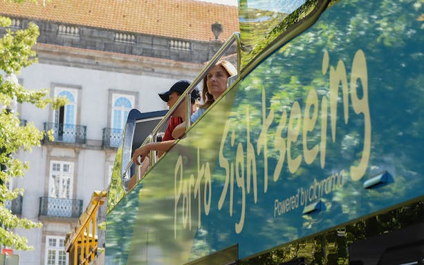Hop-on hop-off bus tour in Porto with passengers on the upper deck.