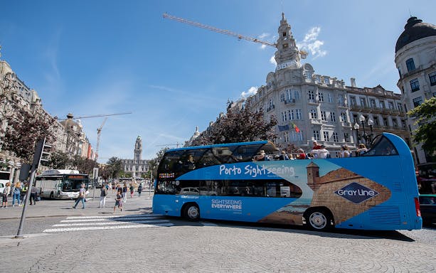 Hop-on hop-off bus in Porto city center with historic buildings in the background.
