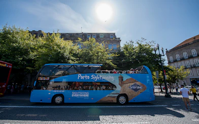 Porto sightseeing bus parked on a city street with tourists on board.