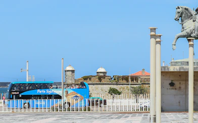 Porto sightseeing bus near historic fort and equestrian statue.