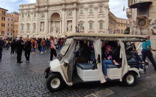 Electric golf cart near Trevi Fountain in Rome with tourists and local guide.