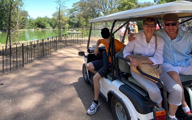 Electric golf cart by a lake in Rome with tourists and local guide.