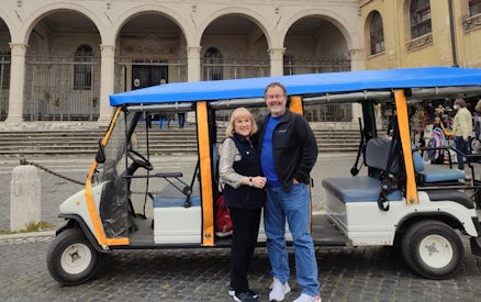 Electric golf cart parked in front of historic building in Rome.