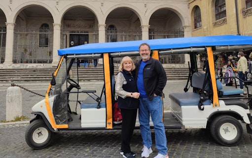 Electric golf cart parked in front of historic building in Rome.