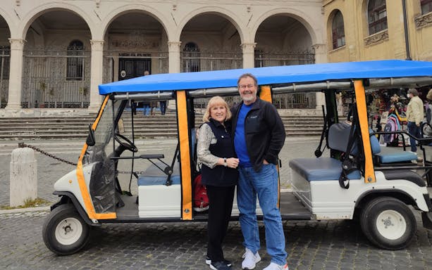 Electric golf cart parked in front of historic building in Rome.