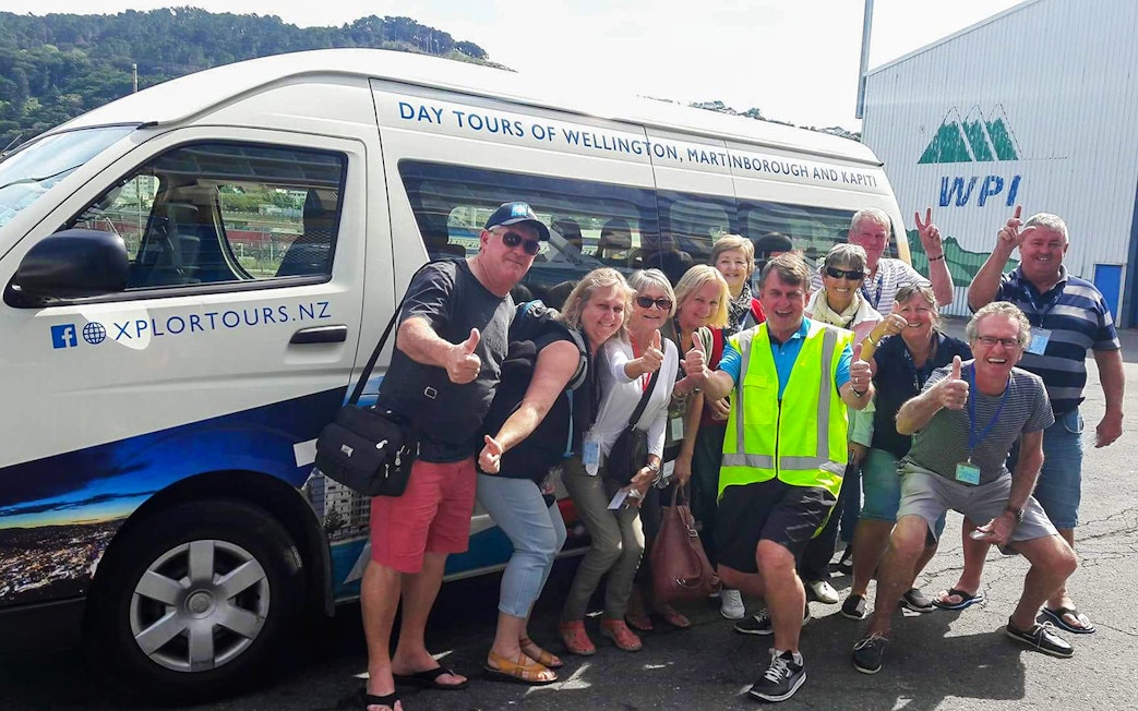 Group of tourists posing with a tour van in Wellington, New Zealand.