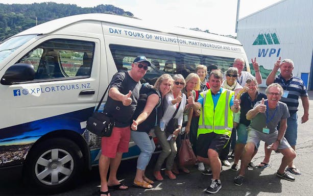 Group of tourists posing with a tour van in Wellington, New Zealand.
