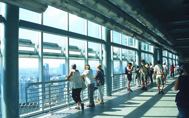 Visitors enjoying city views from Petronas Twin Towers skybridge in Kuala Lumpur.