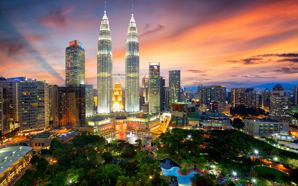Petronas Twin Towers illuminated at sunset in Kuala Lumpur, Malaysia.