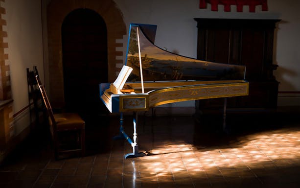 Harpsichord in a sunlit room at Gropparello Castle during guided tour.