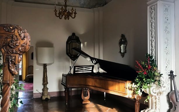 Gropparello Castle interior with grand piano and ornate decor.