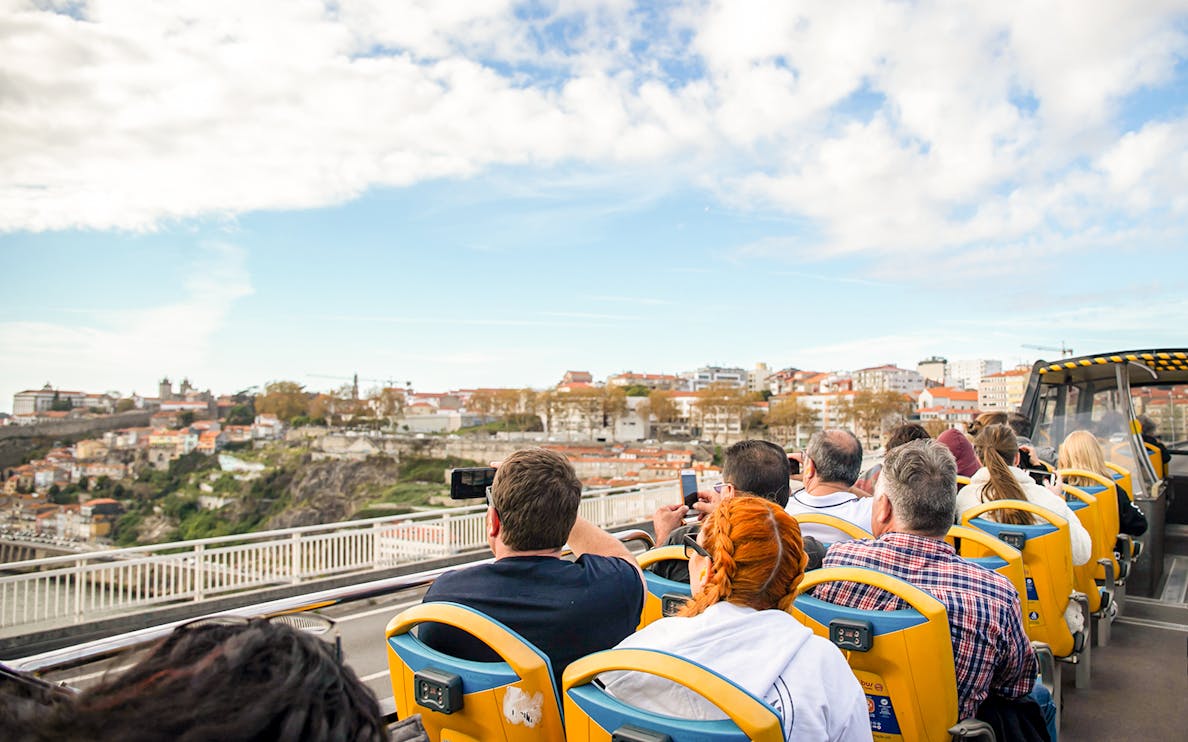 Vintage bus on Porto city tour passing by historic buildings.