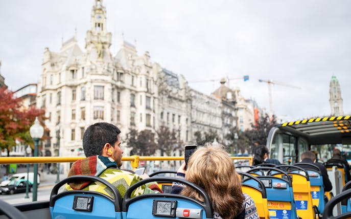 Hop-on hop-off bus tour in Porto passing by historic architecture.