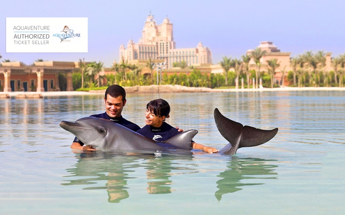 People interacting with a dolphin at Aquaventure Waterpark, Atlantis The Palm, Dubai.