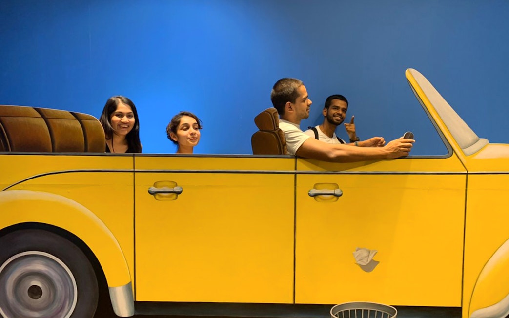 Visitors interacting with a 3D car exhibit at Illusion 3D Art Museum Kuala Lumpur.