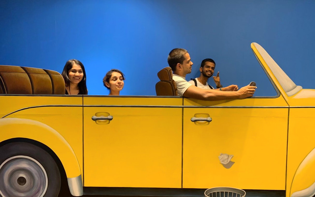 Visitors interacting with a 3D car exhibit at Illusion 3D Art Museum Kuala Lumpur.