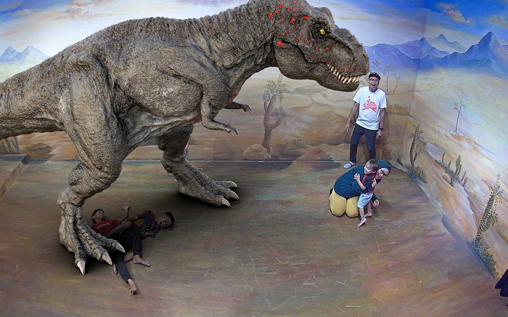 Visitors interacting with a 3D dinosaur illusion at Illusion 3D Art Museum Kuala Lumpur.