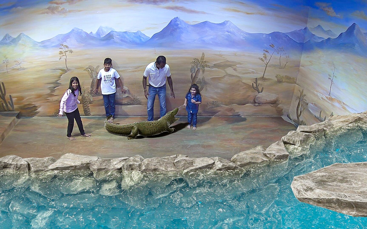 Visitors interact with 3D crocodile art at Illusion 3D Art Museum Kuala Lumpur.