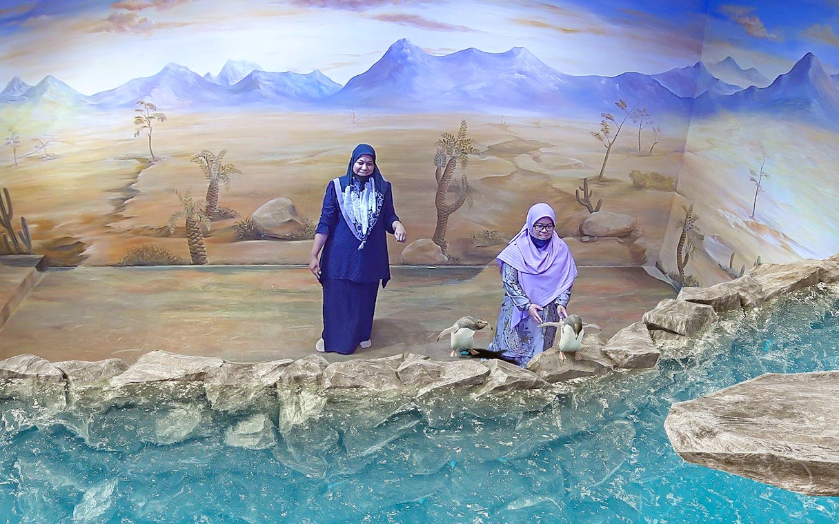 Visitors interacting with 3D penguin art at Illusion 3D Art Museum Kuala Lumpur.