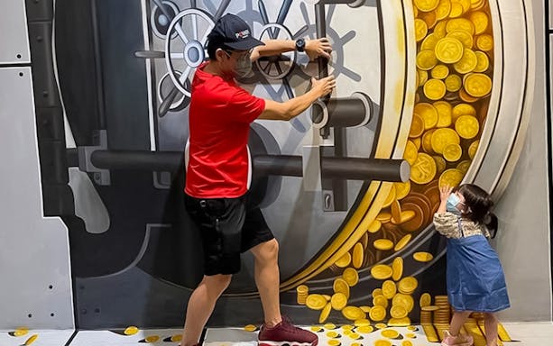 Man and child interacting with 3D vault art at Illusion 3D Art Museum Melaka.