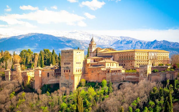Alhambra fortress in Granada with Sierra Nevada mountains in the background.