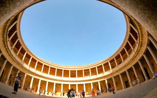 Visitors in the circular courtyard of the Palace of Charles V at Alhambra, Granada.