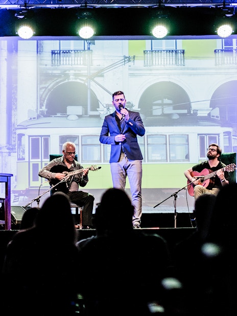 Fado performance in Chiado with musicians and singer on stage, Lisbon backdrop.