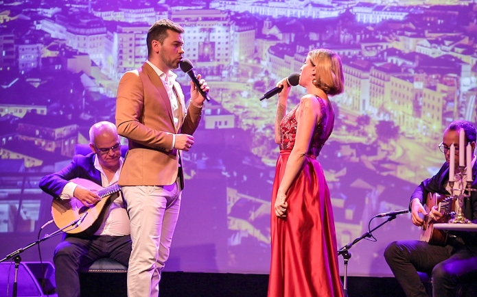 Fado singers performing on stage in Chiado, Lisbon with musicians playing guitars.