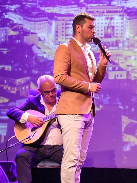 Fado singers performing on stage in Chiado, Lisbon with musicians playing guitars.