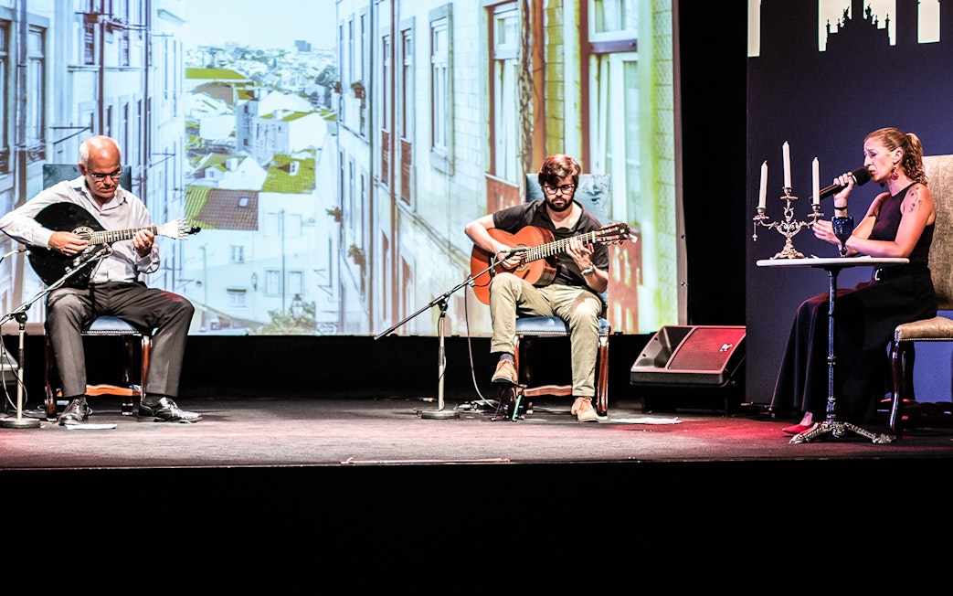 Musicians performing Fado in Chiado, Lisbon, with a backdrop of city buildings.