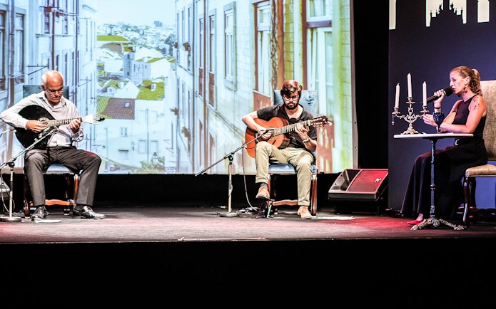 Musicians performing Fado in Chiado, Lisbon, with a backdrop of city buildings.