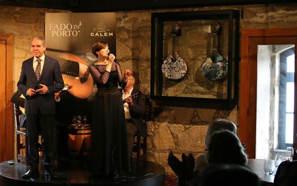 Fado singers performing in a Porto wine cellar with traditional Portuguese guitars.