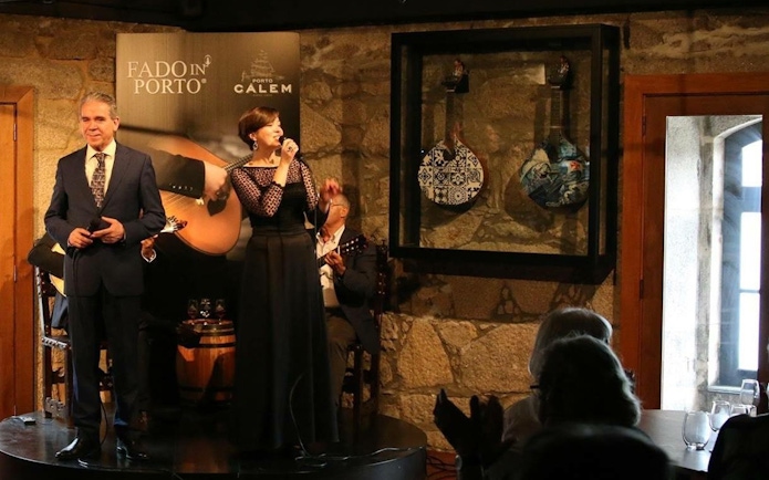 Fado singers performing in a Porto wine cellar with traditional Portuguese guitars.