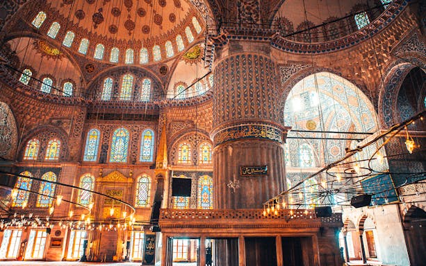 Interior of a mosque in Istanbul with ornate stained glass windows and intricate tile work.