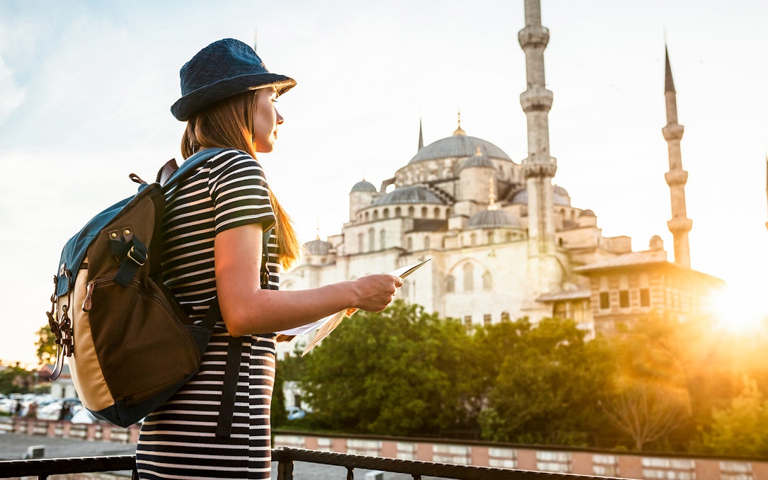 Traveler with a map near the Blue Mosque in Istanbul during sunset.