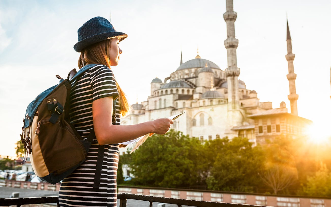 Traveler with a map near the Blue Mosque in Istanbul during sunset.