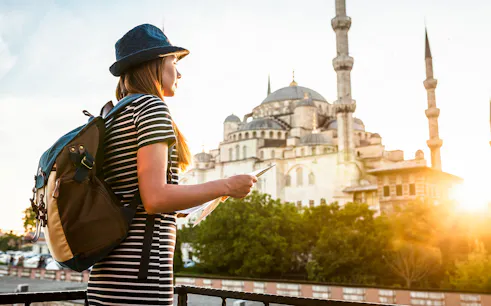 Traveler with a map near the Blue Mosque in Istanbul during sunset.
