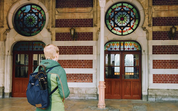 Person with backpack facing stained glass windows at Sirkeci Station, Istanbul.