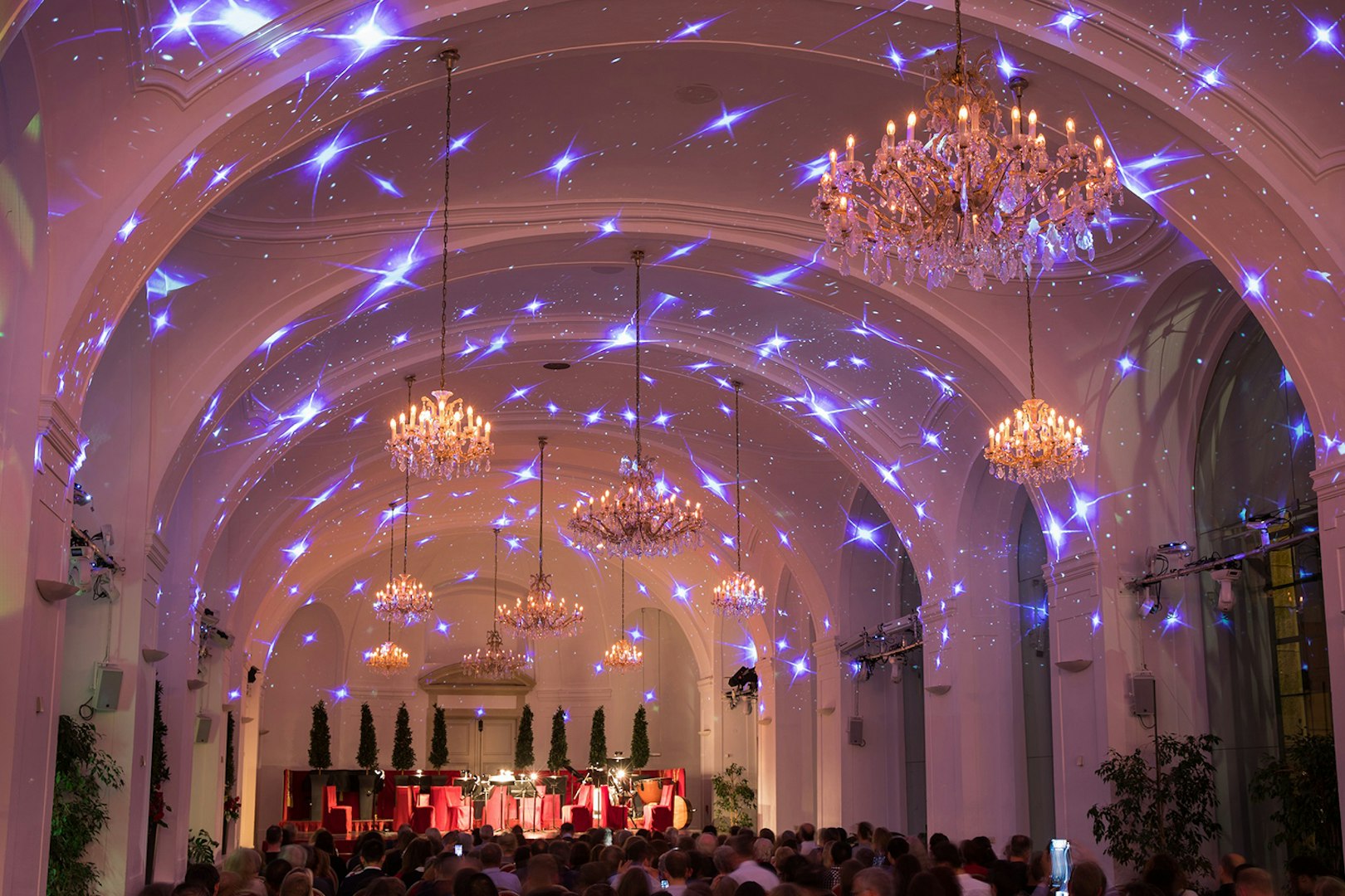Concert hall at Schönbrunn Palace with chandeliers and festive lighting during Mozart & Strauss performance.