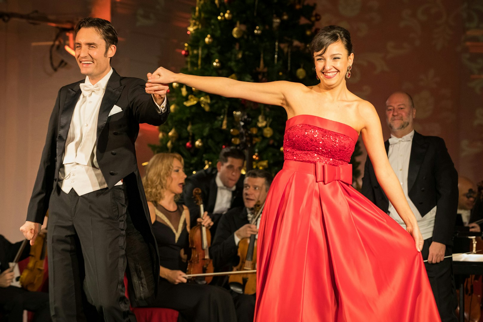 Performers at Schönbrunn Palace concert with orchestra and Christmas tree.