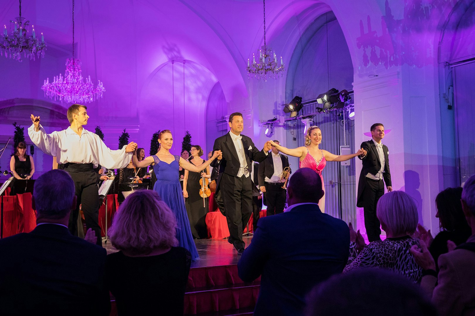 Performers bowing at Schönbrunn Palace concert with audience applauding.