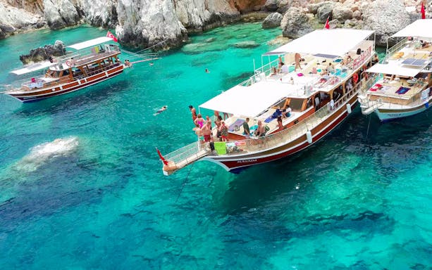 Boats anchored near Suluada Island with tourists swimming in clear water, Antalya/Kemer trip.