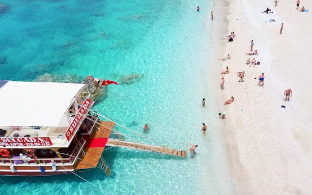 Boat docked at Suluada Island with people enjoying the beach, Antalya/Kemer.