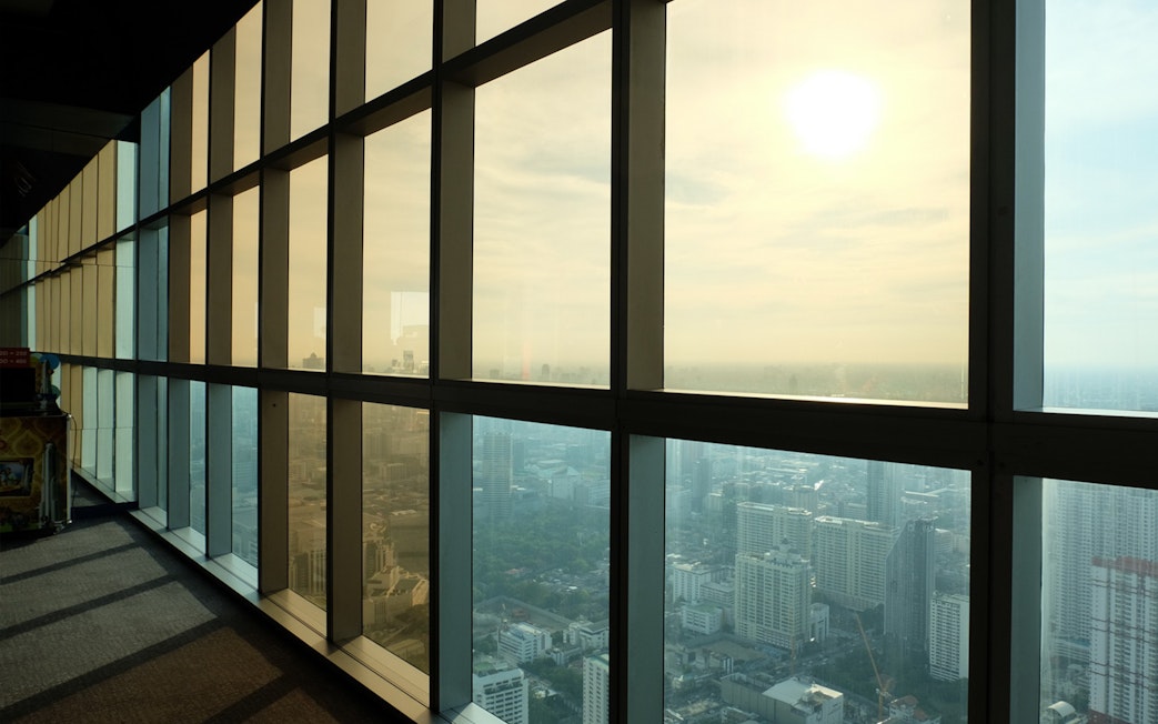 View from Baiyoke Sky Hotel Observatory, Bangkok, showing cityscape through large windows.